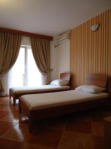 two beds in a room with two windows at Guesthouse Villa Gaga in Budva