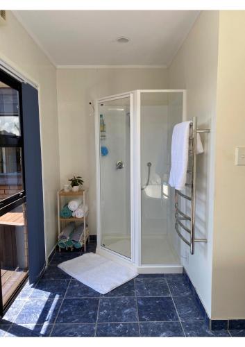 a bathroom with a shower with a glass door at Harbour View Retreat Mangonui in Mangonui