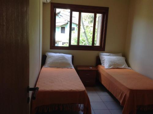 two beds in a small room with a window at Praia Brava Apto 2 dorms Vista ao Mar in Florianópolis