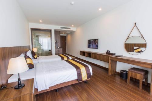 a bedroom with a bed and a desk and a mirror at Sun Bay Tuan Chau Hotel in Ha Long