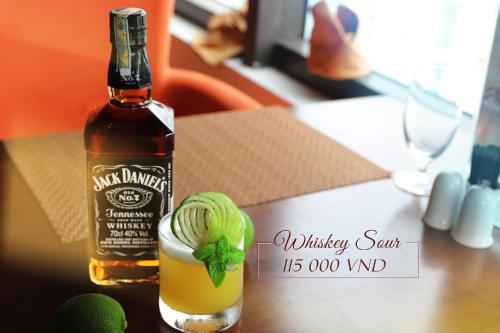 a bottle of whiskey sitting next to a drink at Balcona Hotel Da Nang in Da Nang