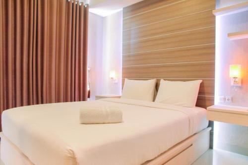 a bedroom with a large white bed with a wooden headboard at Best Price 1BR Apartment at The Oasis Cikarang By Travelio in Cikarang