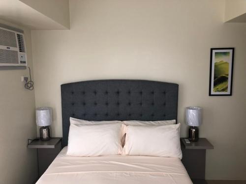 a bedroom with a bed with white sheets and two lamps at Your Own 3 C's Space (Cozy, Clean and Convenient)! in Tagaytay