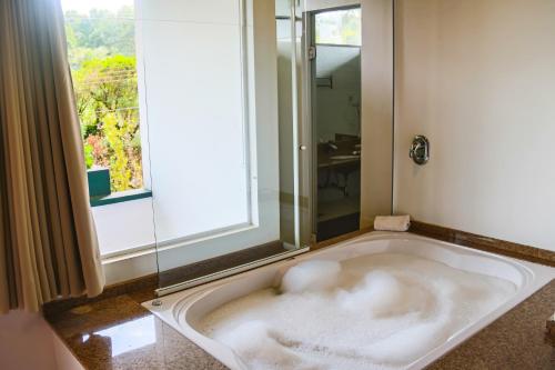 a bath tub in a bathroom with a window at Pousada Encontro da Pedra in Monte Verde