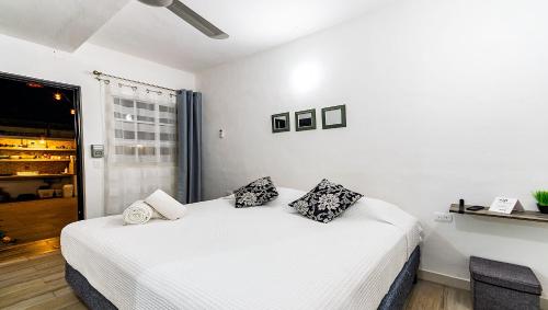 a bedroom with a white bed with pillows on it at Vacation Rental - Standard Room at Casa Cocoa in Cozumel