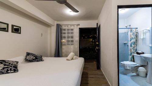 Vacation Rental - Standard Room at Casa Cocoa في كوزوميل: غرفة نوم بسرير ابيض وحمام