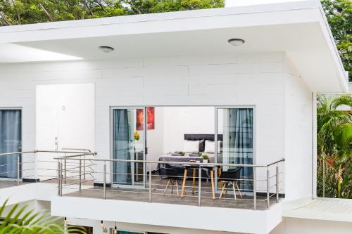 a white house with a balcony with a table and chairs at In the Shade Hotel - Coworking - 300Mbit - Adults Only in Tamarindo