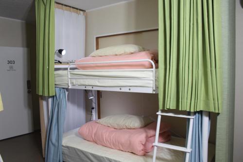 two bunk beds in a room with green curtains at Guesthouse Banvina in Kagoshima
