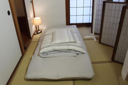 a large white bed in a room with a lamp at Guesthouse Banvina in Kagoshima