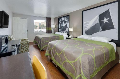 a hotel room with two beds and a flat screen tv at Super 8 by Wyndham San Antonio Pearl District Downtown in San Antonio