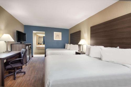 a hotel room with two beds and a desk at Travelodge by Wyndham Deltona in Deltona
