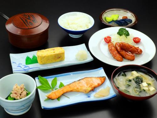 a table with plates of food and bowls of food at Business Hotel Nishikiryu in Kiryu