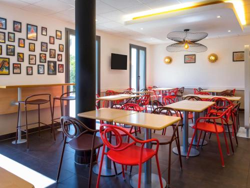 a dining room with tables and red chairs at ibis budget Genève Petit-Lancy in Geneva