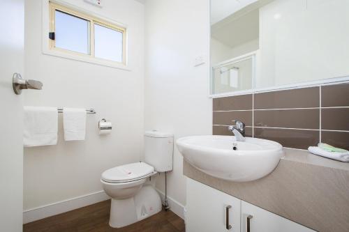a white bathroom with a toilet and a sink at Discovery Parks - Lake Hume, New South Wales in Lake Hume