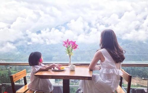 two girls sitting at a table looking out at the mountains at Chau Long Sapa 2 Hotel in Sa Pa