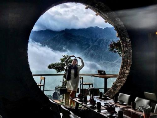 a woman standing in front of a window with a view at Chau Long Sapa 2 Hotel in Sa Pa
