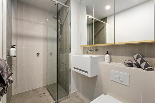 a bathroom with a glass shower and a sink at Luxuria Apartments - Avant in Melbourne