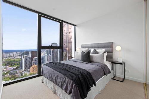 a bedroom with a large bed and a large window at Luxuria Apartments - Avant in Melbourne