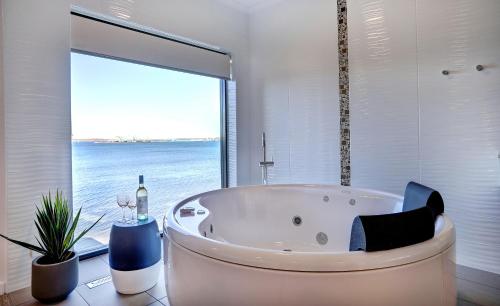 a bath tub in a bathroom with a large window at Limani Motel in Port Lincoln