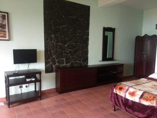 a bedroom with a bed and a tv on the wall at Shamrock Holiday Home in Munnar