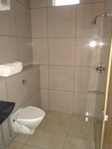 a bathroom with a toilet and a glass shower at Shamrock Holiday Home in Munnar