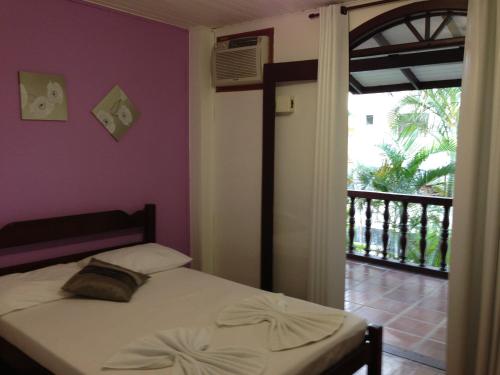 a bedroom with a bed and a door to a balcony at Pousada das Gaivotas in Bombinhas