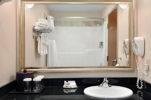 ein Badezimmer mit einem Waschbecken und einem großen Spiegel in der Unterkunft Canalta Hotel Melfort in Melfort