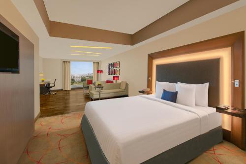 a hotel room with a large bed and a living room at Novotel Ahmedabad in Ahmedabad