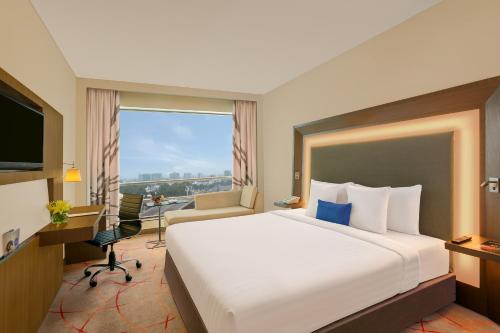 a hotel room with a large bed and a desk at Novotel Ahmedabad in Ahmedabad