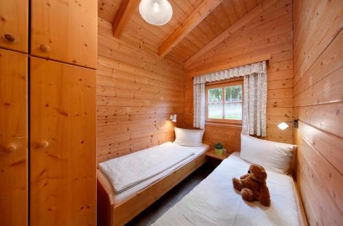 two beds in a log cabin with a teddy bear sitting on them at Knaus Campingpark Lackenhäuser in Neureichenau