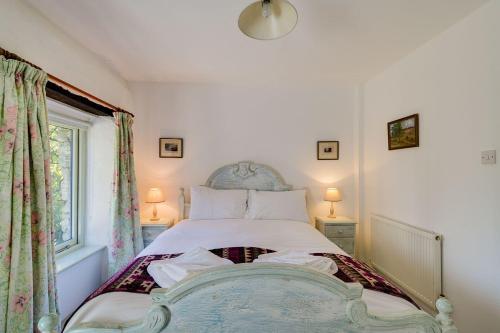 LewannickにあるThe Granary at Trevadlock Manorのベッドルーム1室(ランプ2つ、窓付)