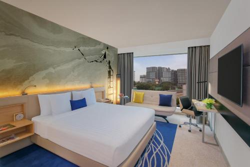 a hotel room with a bed and a tv at Novotel Ahmedabad in Ahmedabad