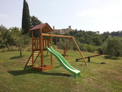 a playground with a green slide in a field at Aurora Agriturismo in San Casciano dei Bagni