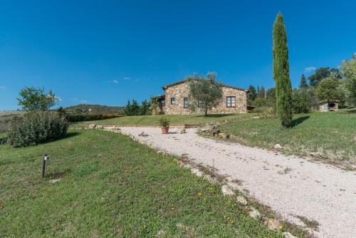 a stone house on a hill with a dirt road at Aurora Agriturismo in San Casciano dei Bagni