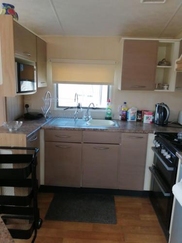 a kitchen with a sink and a stove at Caravan ( Static, within a super holiday park ) in Birchington