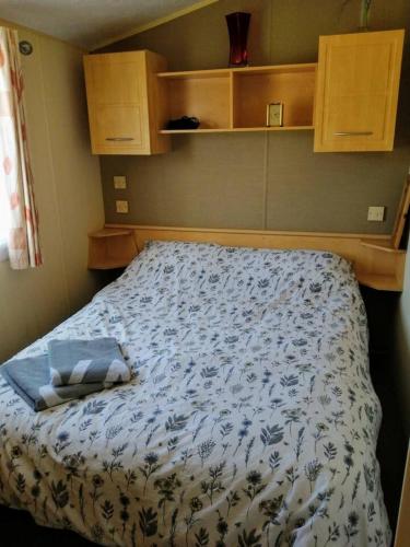 a bedroom with a bed with a blue and white comforter at Caravan ( Static, within a super holiday park ) in Birchington