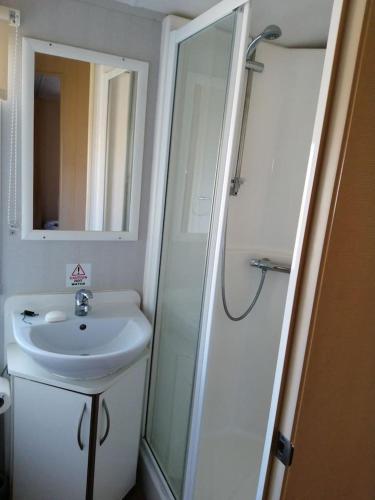 a white bathroom with a sink and a shower at Caravan ( Static, within a super holiday park ) in Birchington