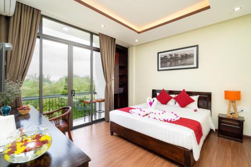 a bedroom with a bed and a balcony at Ancient River Villa in Hoi An