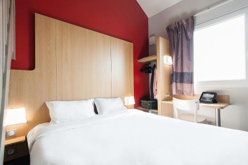 ブルージュにあるB&B HOTEL Bordeaux Lac sur Brugesの白いベッドと赤い壁が備わるベッドルーム1室が備わります。