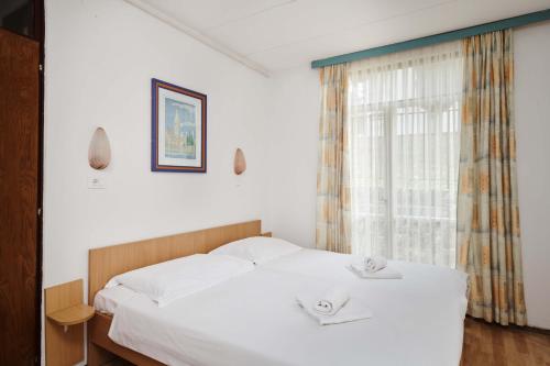 a bedroom with a white bed with two towels on it at Apartments Astra Plava Laguna in Poreč