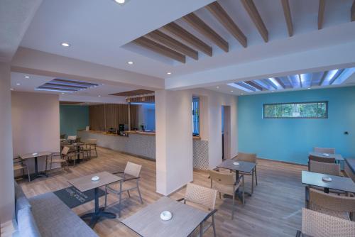 a cafeteria with tables and chairs and a blue wall at Cactus Beach Hotel in Stalida