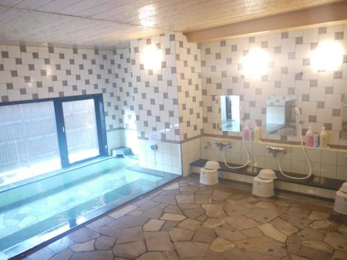 een badkamer met een zwembad en 2 toiletten bij Hotel Route-Inn Abashiri Ekimae in Abashiri