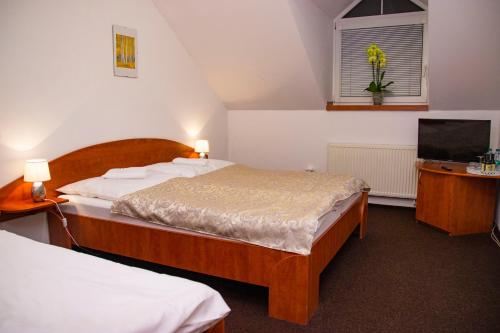 a bedroom with two beds and a flat screen tv at Penzion Axa in Hradec Králové