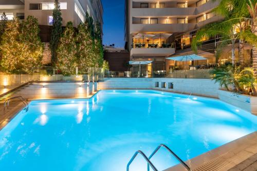 a large swimming pool in a hotel at night at Galaxy Iraklio Hotel in Heraklio Town
