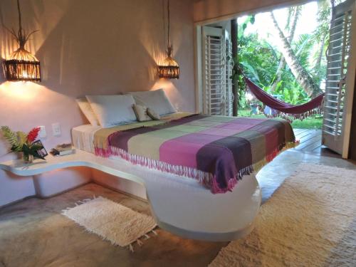 a bedroom with a bed with a desk and a window at Nirvana Beach Hotel in Barra Grande