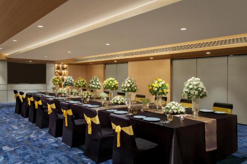 a conference room with a long table with yellow bows at Novotel Ahmedabad in Ahmedabad