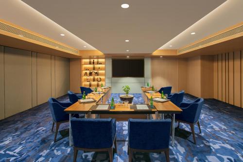 a conference room with a long table and blue chairs at Novotel Ahmedabad in Ahmedabad