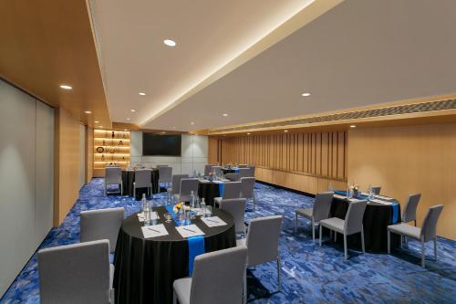 a conference room with tables and chairs and a screen at Novotel Ahmedabad in Ahmedabad