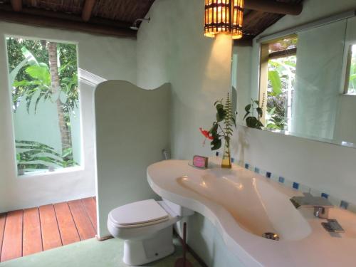 ein Badezimmer mit einem Waschbecken, einem WC und einem Spiegel in der Unterkunft Nirvana Beach Hotel in Barra Grande
