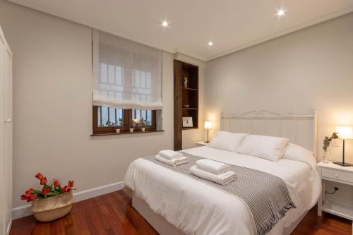 um quarto com uma cama branca e toalhas em RIBERA MARKET by ALOHA Bilbao em Bilbao